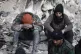 People sit on the wreckage of collapsed buildings, in Aleppo