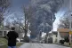 A man takes photos as a black plume rises over East Palestin