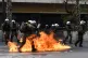 Riot police take their positions next to flames from Molotov