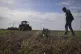 A farmer looks at a part of a Russian rocket in an agricultu