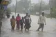 People wade through a flooded street following heavy winds a