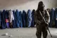 A Taliban fighter stands guard as women wait to receive food