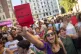 A demonstrator holds a red card reading in Spanish 
