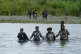 Haitian migrants wade across the Tuquesa river after trekkin
