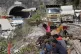 People sit near the site of an under-construction road tunne