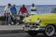 People sit on the malecon with an image of Fidel Castro as t