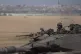 Israeli soldiers move on the top of a tank near the Israeli-