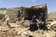 An Afghan couple sit near their damaged home after heavy flo