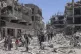 Palestinians walk through the destruction in the wake of an 