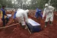 Workers in protective gear lower a coffin of a Covid-19 vict