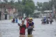 People wade through a flooded street in Biyagama, a suburb o