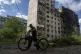 A local man hauls his bicycle in front of an apartment build