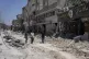 Palestinians walk along a damaged road following an Israeli 