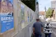 A couple walks past electoral posters showing far-right lead