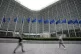 European Union flags wave in the wind as pedestrians walk by