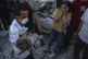 A Palestinian girl reacts as a child is carried from the rub