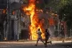 Men run past a shopping centre which was set on fire by prot