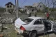People walk in front of their damaged houses after Russian r