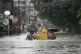 A resident rides an old refrigerator to avoid a flooded stre