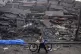 A Palestinian child walks with a bicycle by the rubble of a 