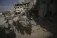 Israeli soldiers take up position next to buildings destroye