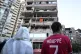 People look up at a damaged building that was hit by Israeli