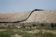 US Border Patrol vehicles survey a steel fence at the Southw