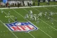 Players compete during a football game between the NFL Acade