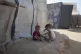 Displaced Palestinian children sit next to their tent in Dei