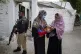 A police officer stands guard as a health worker, right, adm