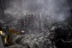 An excavator sifts through the rubble as rescue workers sear