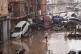Residents look at cars piled up after being swept away by fl