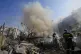 Civil defense workers extinguish a fire as smoke rises from 
