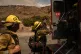 Firefighter Geo Mulongo (centre) finishes his water while ta