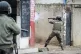 A police officer aims his weapon at protesters in Maputo, Mo