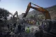 Rescue workers use excavators to remove the rubble of a dest
