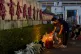 A man lights a candle near flowers placed outside the 