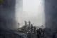 Civil defence workers extinguish a fire as smoke rises from 