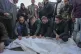 Palestinians mourn over victims during their funeral after a