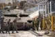Israeli soldiers fix a tank next to the security fence near 