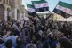 Syrians wave the country's new flag as they gather for Frida