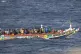 People in a crowded wooden boat sail to the port in La Resti
