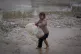 A young girl walks barefoot, carrying empty jerrycans to col