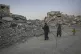 Followed by a young girl, two Palestinian women carry metal 