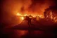 A firefighter battles the Palisades Fire as it burns a struc