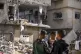 Palestinians look at a damaged residential building followin