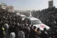 A crowd surrounds Red Cross cars as they arrive at the site 