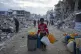 A young Palestinian kid carries jerricans along the destruct