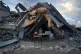 A man sells bread under the ruin of his bakery destroyed by 
