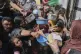 Palestinians wait to get donated food at a distribution cent